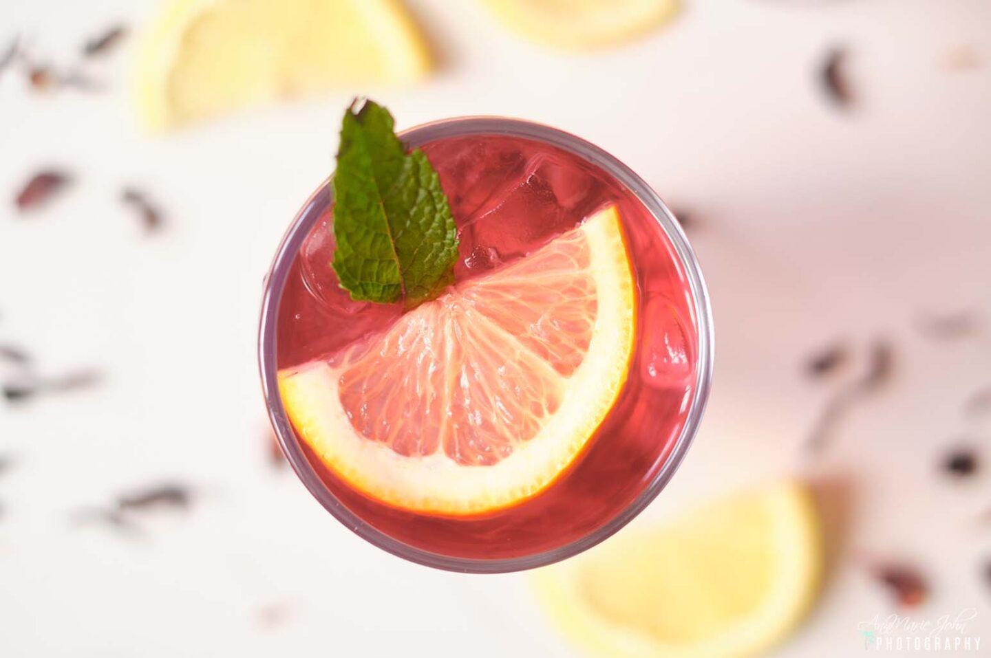 Glass of Hibiscus Iced Tea With Lemon Garnished with Mint and Lemon Slices